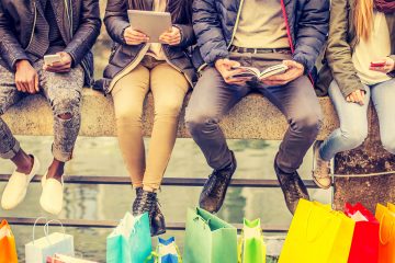 People sitting in a row with shopping bags