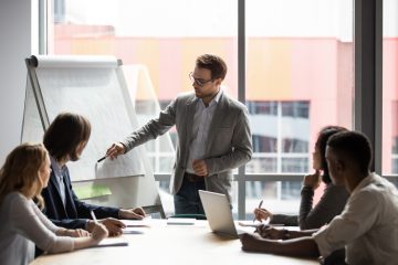 Businessman showing colleagues something on whiteboard